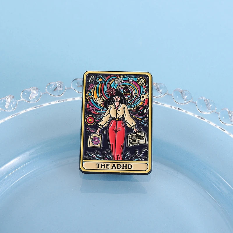 A tarot card enamel pin featuring a woman surrounded by colorful cosmic elements and the text THE ADHD.