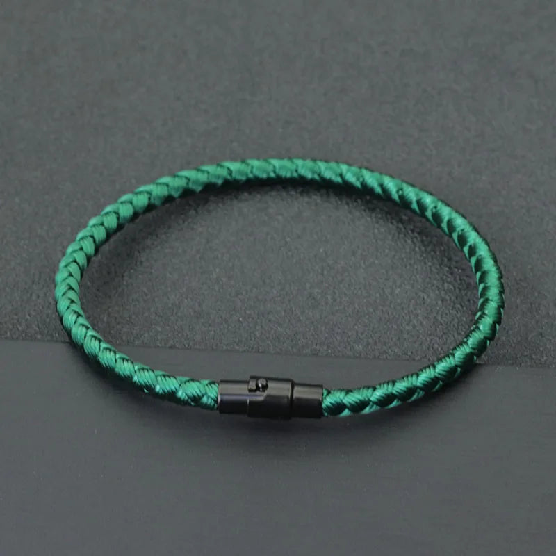 A green thread charm bracelet is displayed on a dark gray surface.