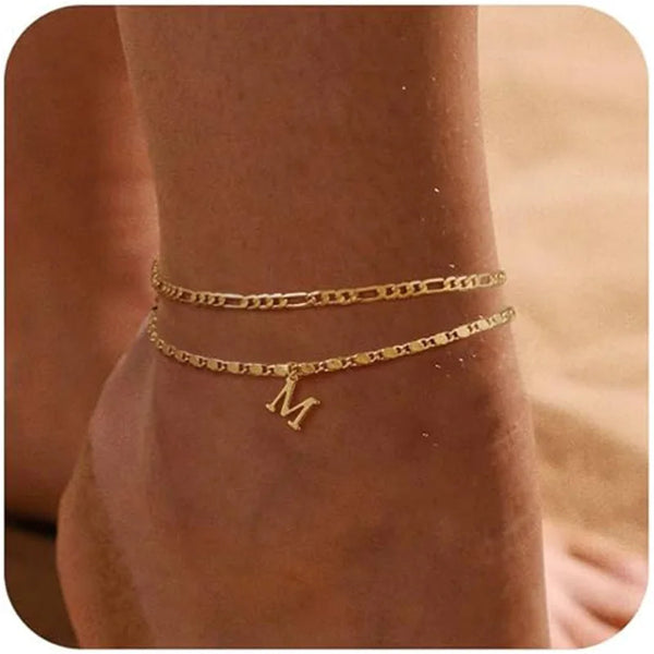 Bracelet-anklet à couches dorées porté au poignet.