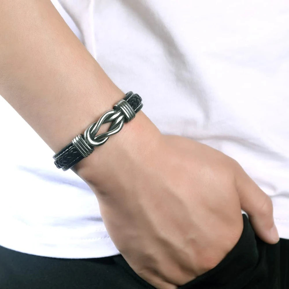 A close-up of a person's wrist wearing a black leather knot bracelet.