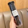 Un contenedor de plástico transparente con gomas para el cabello de rayas onduladas y color caramelo negro, sostenido por una