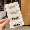 Gold-toned hairpin pins featuring small white pearls and black beads displayed on a white card.