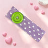A purple fabric headband with white hearts and a bright green button, surrounded by pink heart-shaped objects.