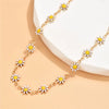 Gold enamel daisy chain anklet with white and yellow flowers displayed on a light background.