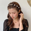 Une femme aux longs cheveux bruns porte un haut noir et un délicat accessoire de cheveux en perles.