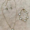 Pulsera y collar de flor de planta de acero inoxidable chapado en oro, mostrados sobre un fondo rosa claro y peludo