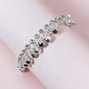 Silver bell foot chain anklet bracelet with small silver charms on a pink background.