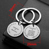 Two personalized stainless steel keychains featuring names and hearts on a black surface.