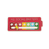 A red brooch pin labeled MY SOCIAL BATTERY featuring multiple small facial expressions.