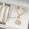 A set of gold-toned quartz jewelry including a necklace, earrings, and ring displayed in a white box.