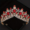 Une tiara et couronne ton or, ornées de gemmes rouges et de cristaux clairs.