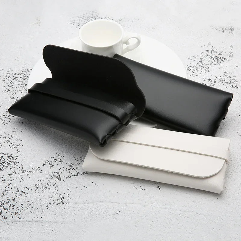 Black and white leather eyeglass cases resting on a white plate.