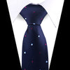 A dark blue patterned silk necktie with scattered pink and blue floral dots shown against a white shirt.