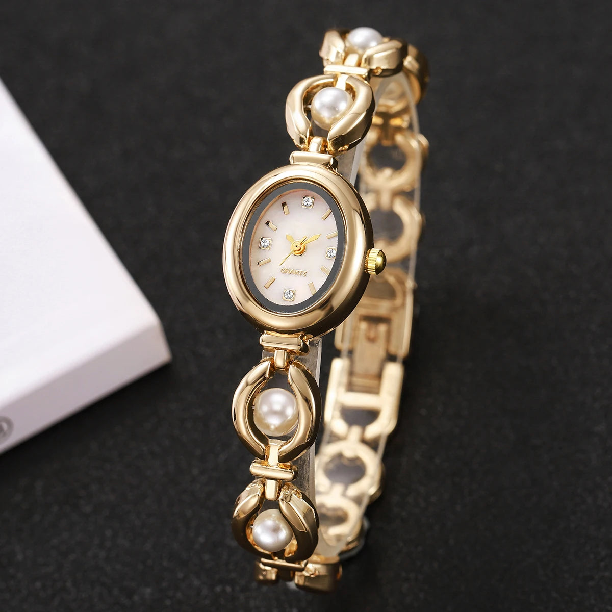 Elegewäsche Goldtonige Perlmutt-Quarz-Armbanduhr mit rundem Zifferblatt und dekorativen Gliedern.