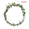A green floral wreath headband made of leaves and small white flowers.