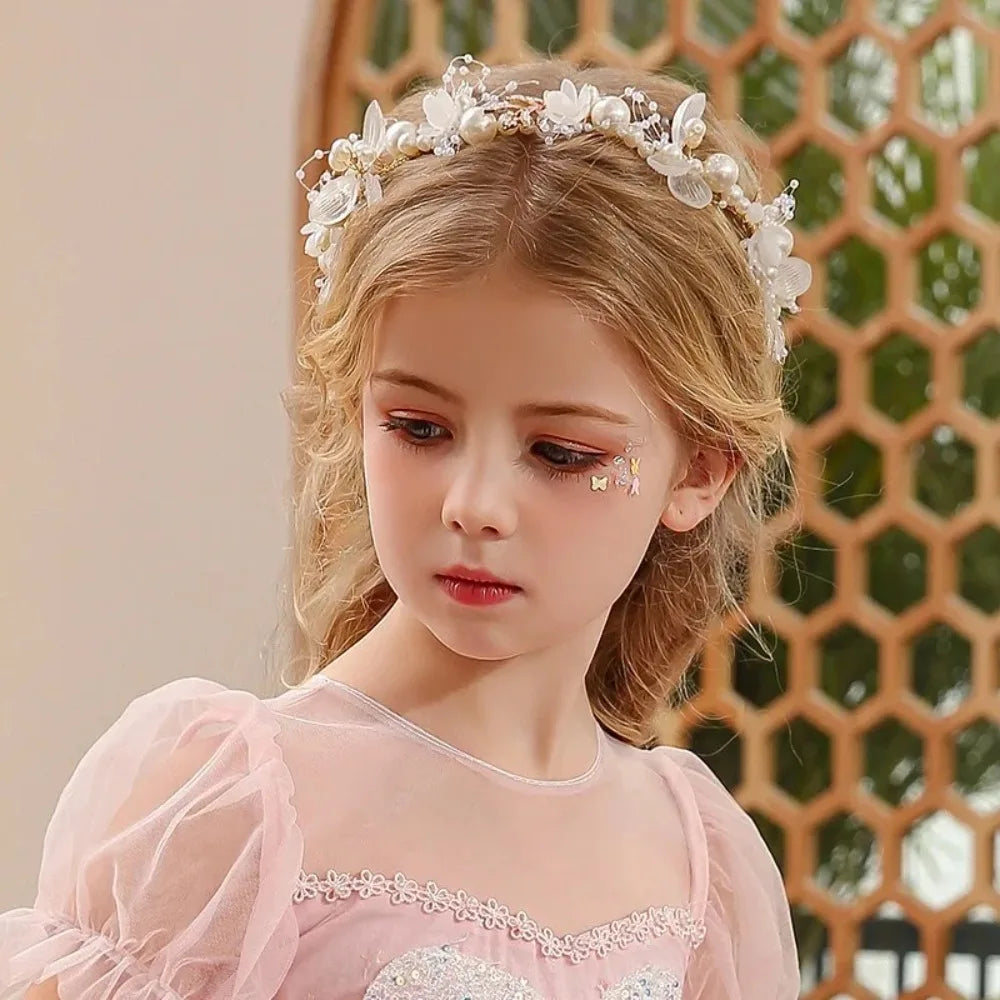 A young girl wearing an elegant floral wreath headband and a pink dress.