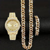 Ensemble de bijoux en chaîne cubaine dorée, comprenant une montre et une longue chaîne, sur fond noir.