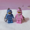 A pair of heart-shaped building block keychains featuring shark figures in blue and pink.