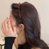 A close-up of a woman's dark hair styled with a multi-layer braided headband clip.