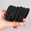 A hand is holding a stack of black elastic hair bands for ponytail and hair ties.
