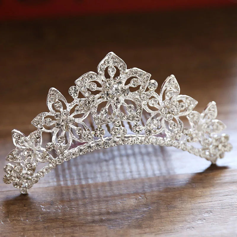 A sparkling crystal princess tiara hair comb for women displayed on a wooden surface.