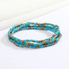 Una pila de pulseras de cuentas azules y bronce sobre un fondo blanco.
