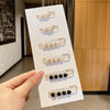 A display of various pearl brooch pins in gold-toned metal, ranging from white to black beads.