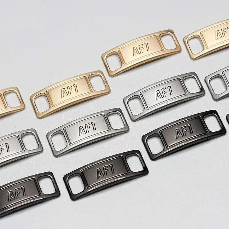 A collection of metal AF1 shoe charms and laces in various finishes including gold, silver, and black.