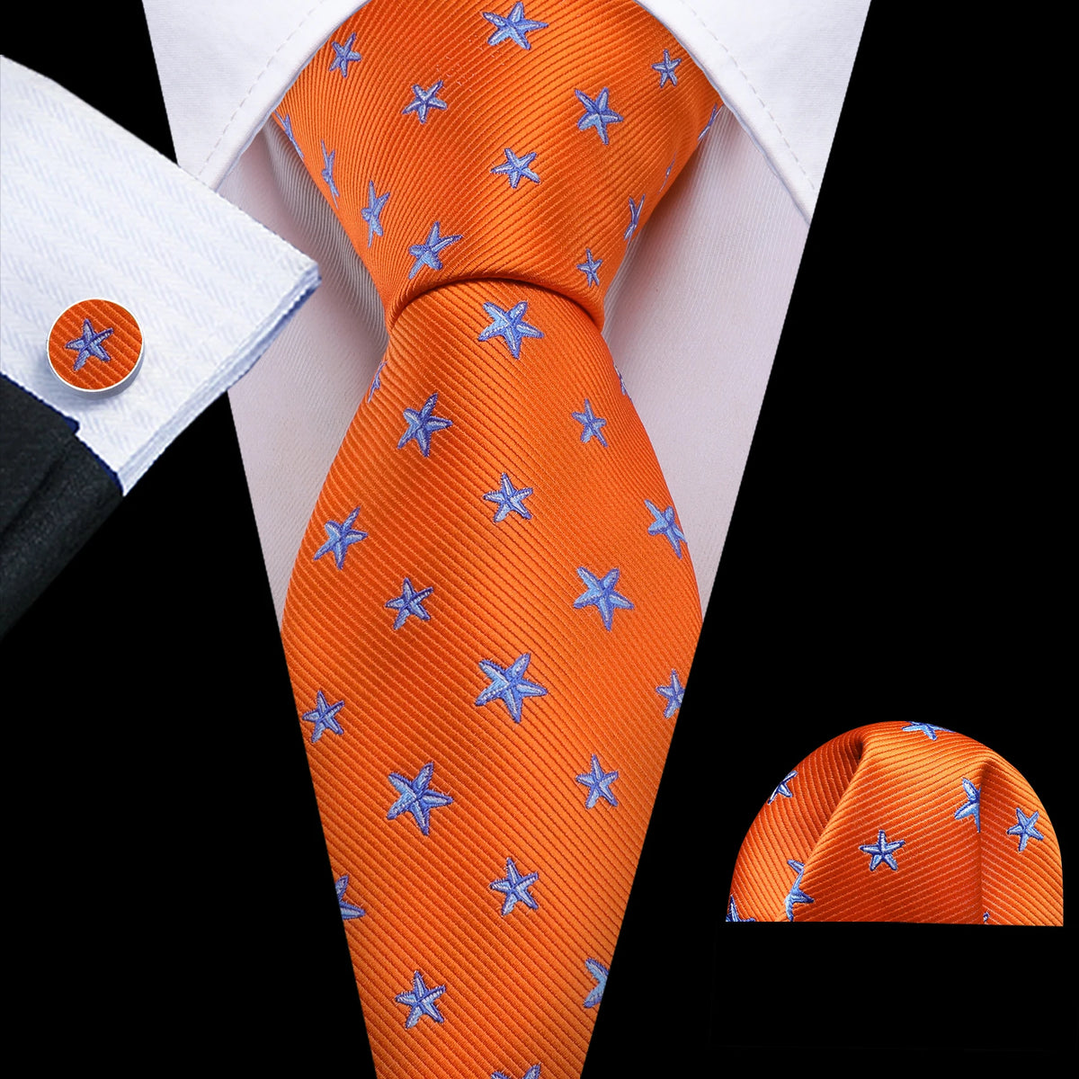 Orange silk jacquard tie featuring blue star patterns worn with a white dress shirt.