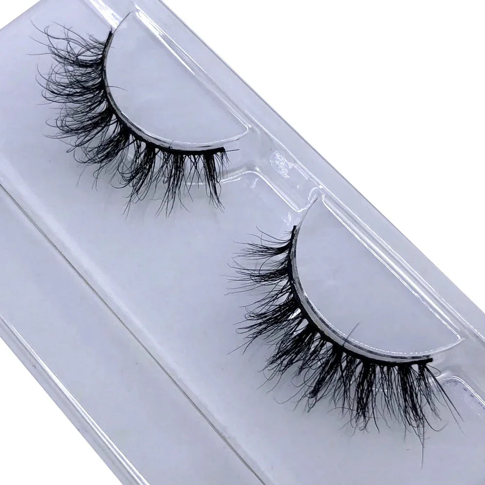 A pair of natural mink false eyelashes displayed in a clear plastic container.
