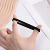 A hand is holding a black elastic hair band against a white background.