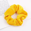 A set of six yellow velvet scrunchies for hair ties displayed on a white background.
