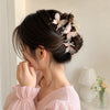 A woman with dark hair is shown in a side profile wearing a pink blouse and a pearl rhinestone butterfly hair claw clip in he