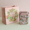 A pink decorative tinplate candy box with a carrying loop featuring illustrations of treats and animals.
