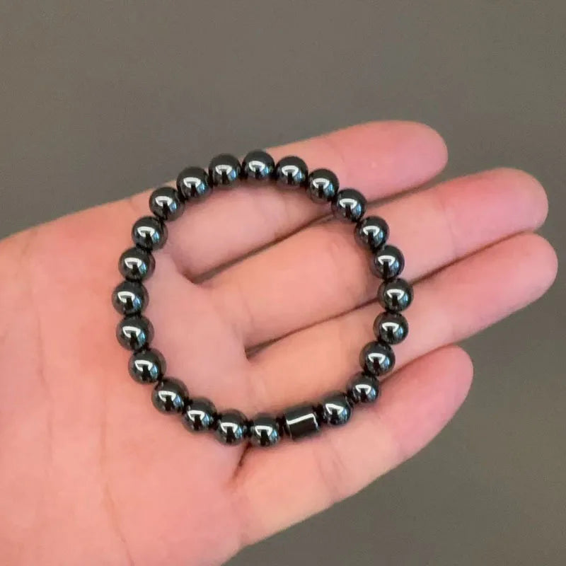 A hand holds a dark blue tiger eye lava map bracelet with small, polished beads.