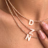 A close-up of a delicate pearl necklace featuring the initial D charm and a crystal pendant.