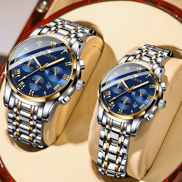 A pair of stainless steel couple quartz watches with blue dials and gold accents resting on a light-colored surface.