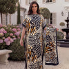 A woman models a black and gold leopard zebra print maxi kaftan outdoors in a garden setting.