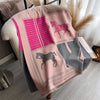 A pink and gray plaid cashmere feel scarf draped over a light-colored surface.