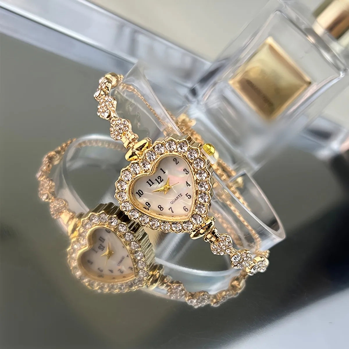 A sparkling heart rhinestone quartz watch is displayed on a clear stand.