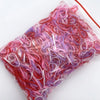 A clear plastic bag filled with colorful disposable hair scrunchies in shades of pink and purple.