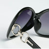 Schwarze Oversized-Sonnenbrille mit silberner Hardware in Nahaufnahme.