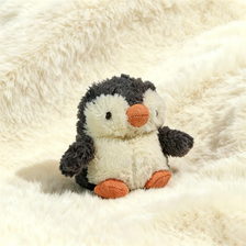 Un jouet de pingouin en peluche gris clair et blanc posé sur une surface blanche et duveteuse.