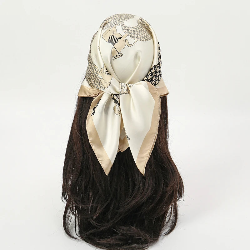 A silk scarf and headband set featuring a cream-colored fabric with black and gold patterned accents tied in a bow.