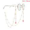 Gold chain necklace with butterfly pendants and round-framed glasses.