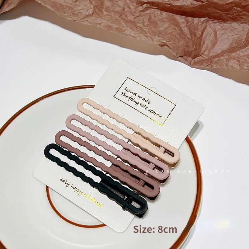 A set of vintage frosted geometry hair clips in various shades of beige and brown displayed on a white plate.