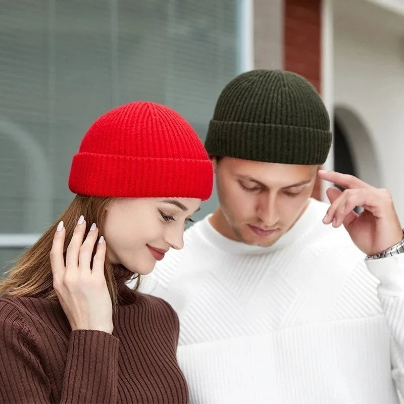 A woman and a man looking down while wearing warm knitted beanie caps.