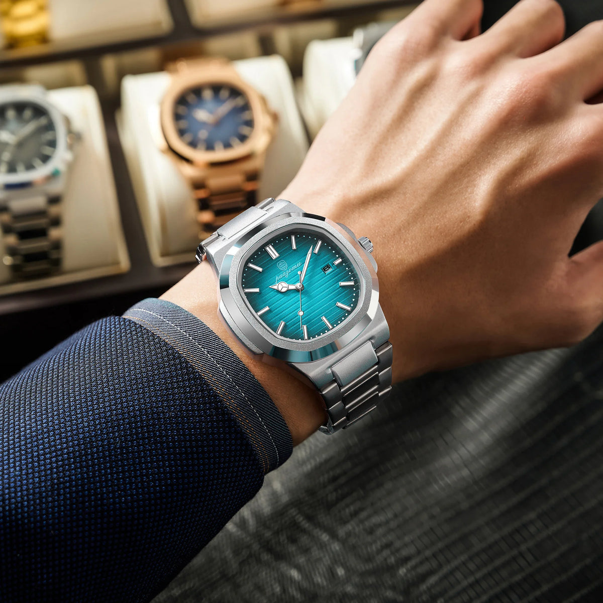 A hand wearing a silver-toned luxury quartz wristwatch with a blue luminous dial and stainless steel bracelet.