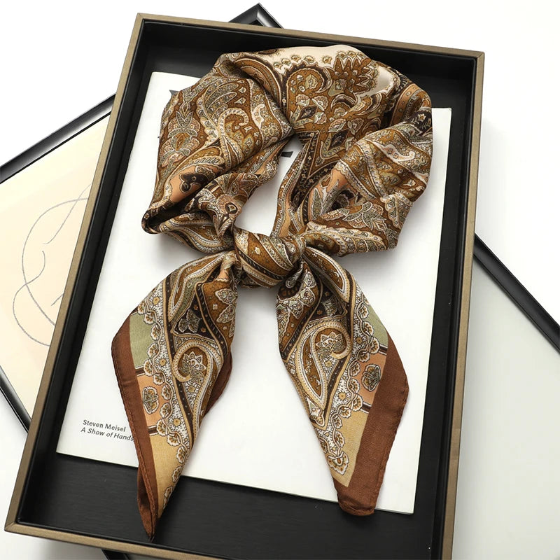 A brown and gold patterned silk scarf tied in a bow displayed in a black frame.