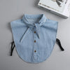 A light blue denim blouse with a false collar detail and buttons is displayed on a gray background.